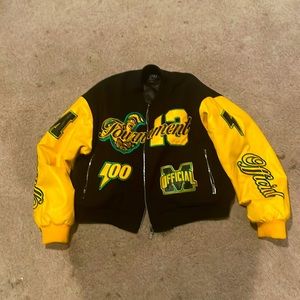 This is a black and yellow varsity jacket with a some green and cropped